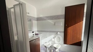 A modern bathroom with two toilets, a shower, and a vanity. - Lercarappart 1 (Lercara Friddi)