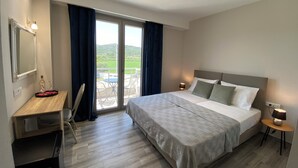A hotel room with a bed, desk, and a balcony with a table and chairs. - Vians Olympia Resort (Pyrgos)