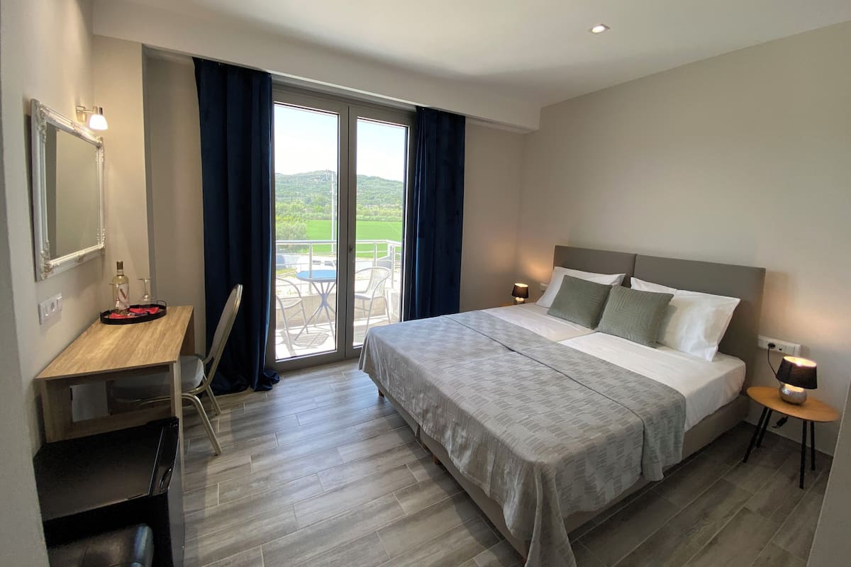 Une chambre d’hôtel avec un lit, un bureau et un balcon équipé d’une table et de chaises.