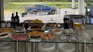A breakfast buffet with various food items and a view of a blue truck outside. - Vians Olympia Resort (Pyrgos)