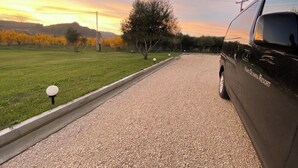 A gravel driveway leading to a black car parked on the side of a road. - Vians Olympia Resort (Pyrgos)