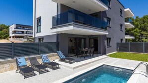 Ein modernes, mehrgeschossiges Gebäude mit Schwimmbad, Außenbereich und einem gepflegten Garten.