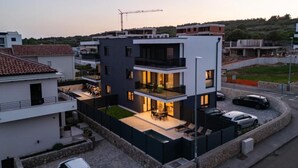 Ein modernes Wohngebäude mit zwei Etagen, einem Balkon und einer Außenbereich-Sitzgelegenheit.