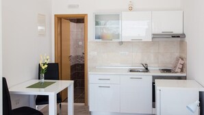 Eine kompakte Küche mit weißen Schränken, einem eingebauten Backofen und einem kleinen Kühlschrank.