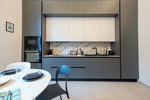 A modern kitchen with built-in appliances, a marble backsplash, and a dining area with a table set for two.
