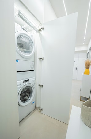 A modern laundry room with a large industrial washer and dryer, a white door, and a clean, minimalist design.