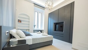 Quarto moderno com cama, mesa de cabeceira, televisão e estantes embutidas.