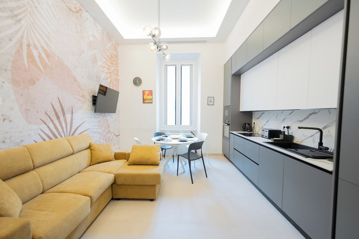 Ein stilvolles Wohnzimmer mit Sofa, Esstisch und Küchenzeile.