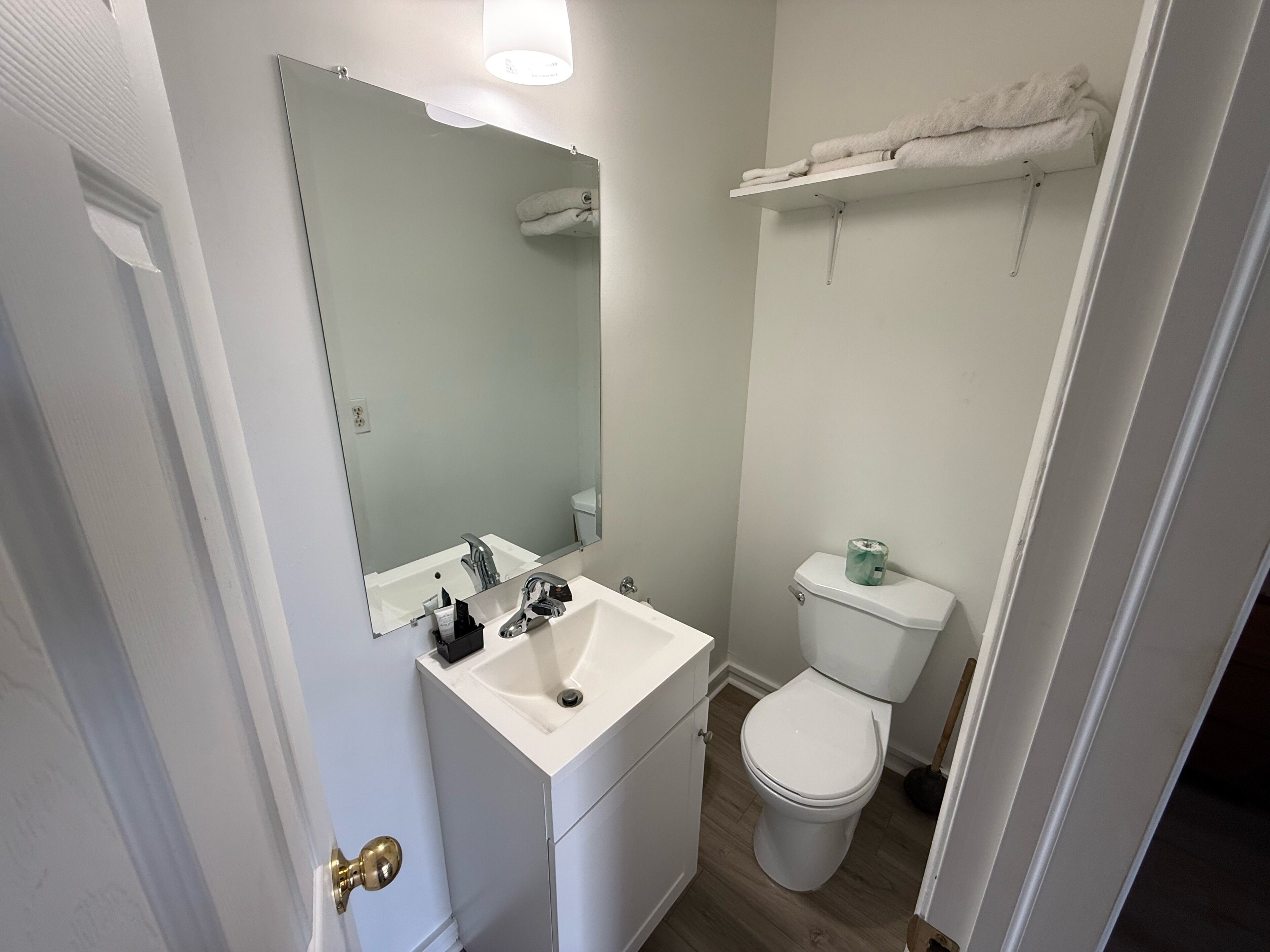 Ein Badezimmer mit weißem Waschbecken, Spiegel, Toilette und Handtuchhalter.