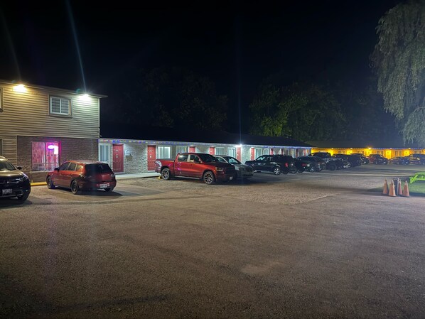 A motel with multiple rooms, a parking lot, and a row of parked cars. - COUNTRY INN MOTEL (Dunnville)