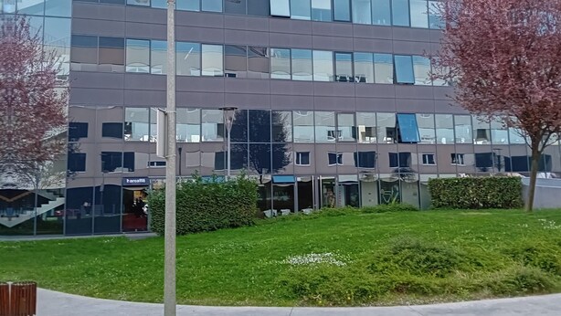 Un edificio moderno con varios pisos, amplias ventanas y una entrada visible.