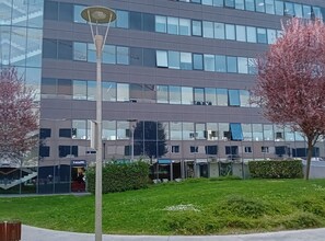 Un edificio moderno con varios pisos, amplias ventanas y una entrada visible.