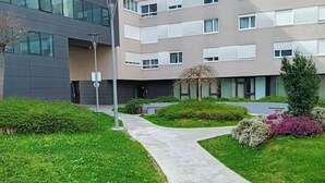 Un edificio moderno con un jardín ajardinado, un camino y una farola.