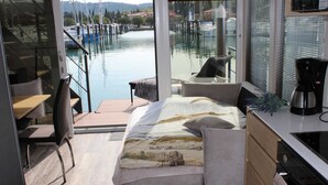 A modern bedroom with a bed, a desk, and a view of a marina. - The Seaborn Residence (Piran)