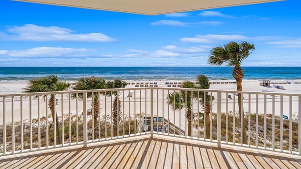 Una terraza de madera con vista a una playa y el océano.