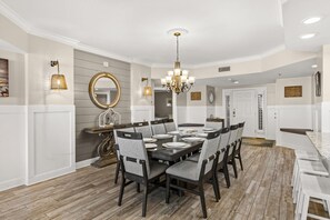 Un comedor con una mesa grande dispuesta para seis personas, rodeada de sillas con asientos acolchados.