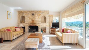 A spacious living room with a stone fireplace, two sofas, a coffee table, and a TV.