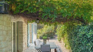 A stone patio with a table and chairs, a bench, and a lantern.
