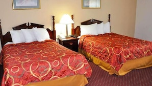 A hotel room with two double beds, each with a red and gold patterned bedspread, a wooden headboard, and a nightstand with a lamp. - Avalon Inn (Sandusky)