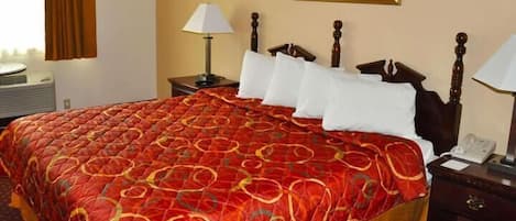 Habitación de hotel con una cama grande, una mesita de noche con lámpara, un cuadro en la pared y una ventana con cortinas.