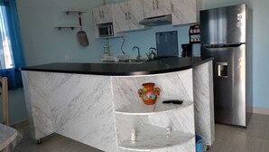 A modern kitchen with a marble island, stainless steel appliances, and a built-in microwave.