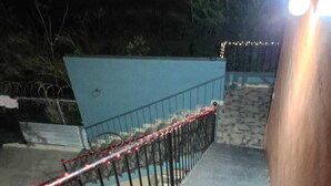 A staircase with a metal railing, leading to a blue wall.