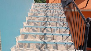 A set of stone steps with blue accents leading up to a black metal railing.