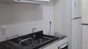 Una cocina compacta con encimera negra, pileta de acero inoxidable y horno empotrado.