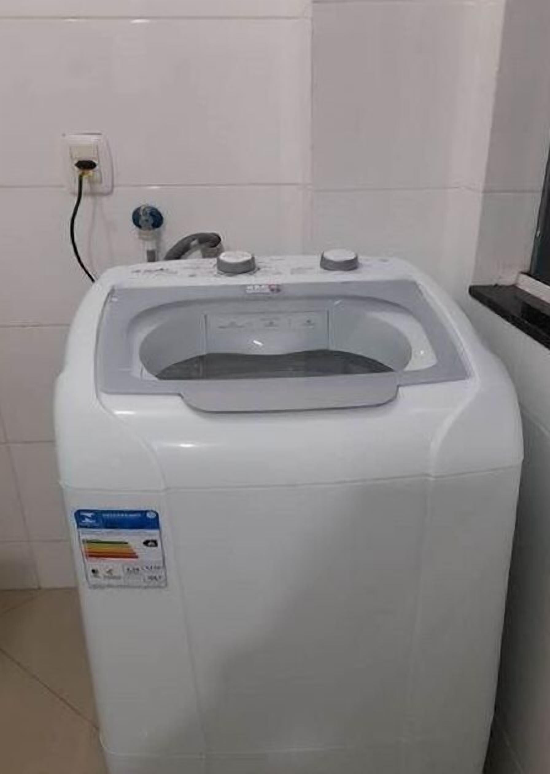 A white water dispenser with a label, a faucet, and a hose.