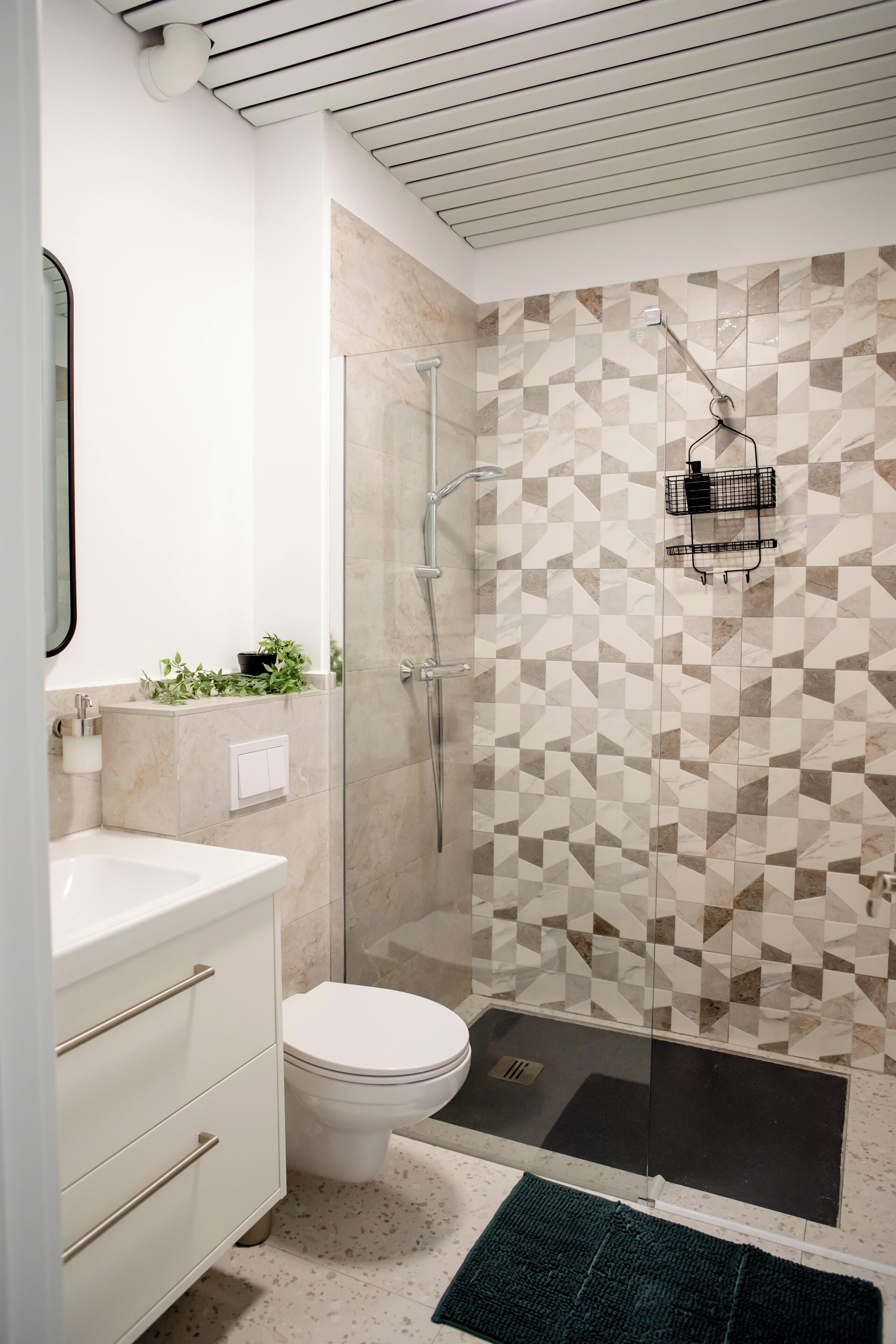 A modern bathroom with a white sink, toilet, and shower.