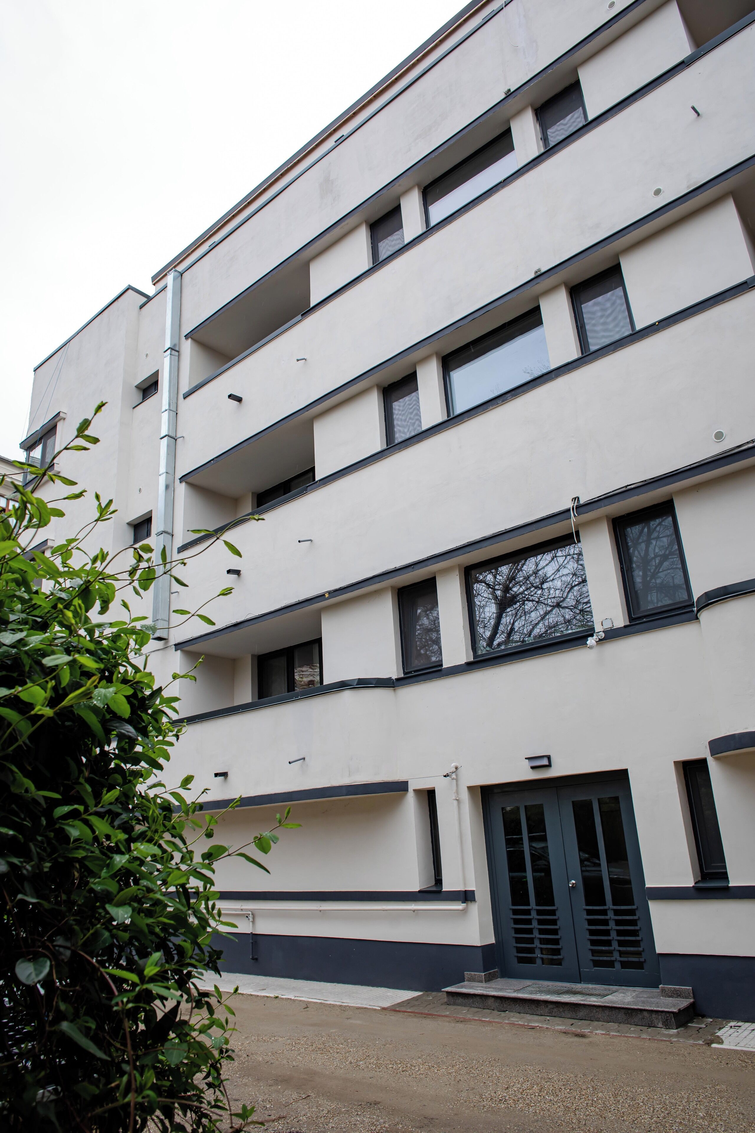 Un immeuble à plusieurs étages doté d’une façade plane, de nombreuses fenêtres et d’une entrée centrale avec une porte.