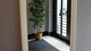 A hallway with a potted plant, a doormat, and a door with a view of the outside. - Little Bucharest downtown apartments (Bucharest)