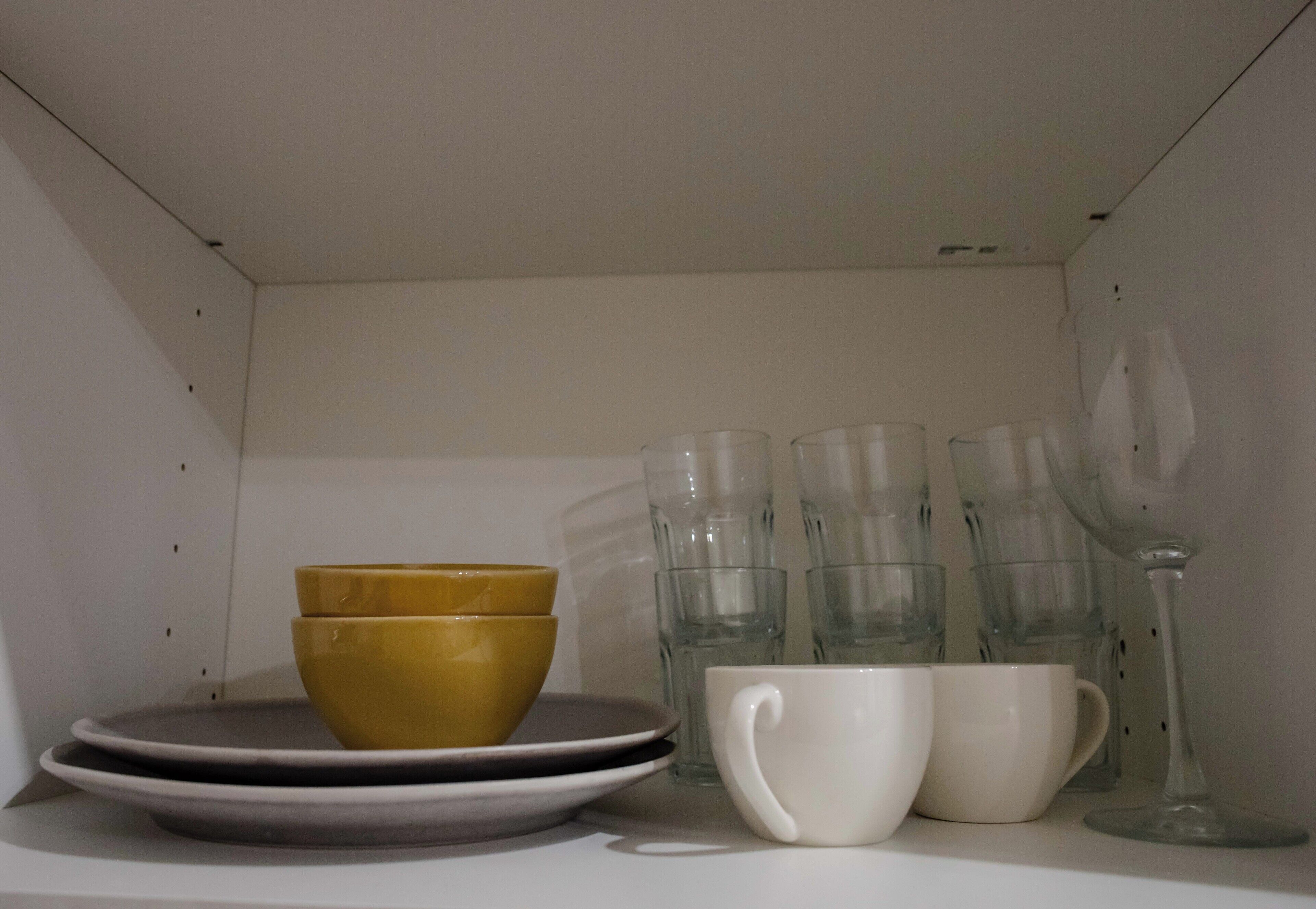 A shelf with stacked bowls, plates, and clear glassware.