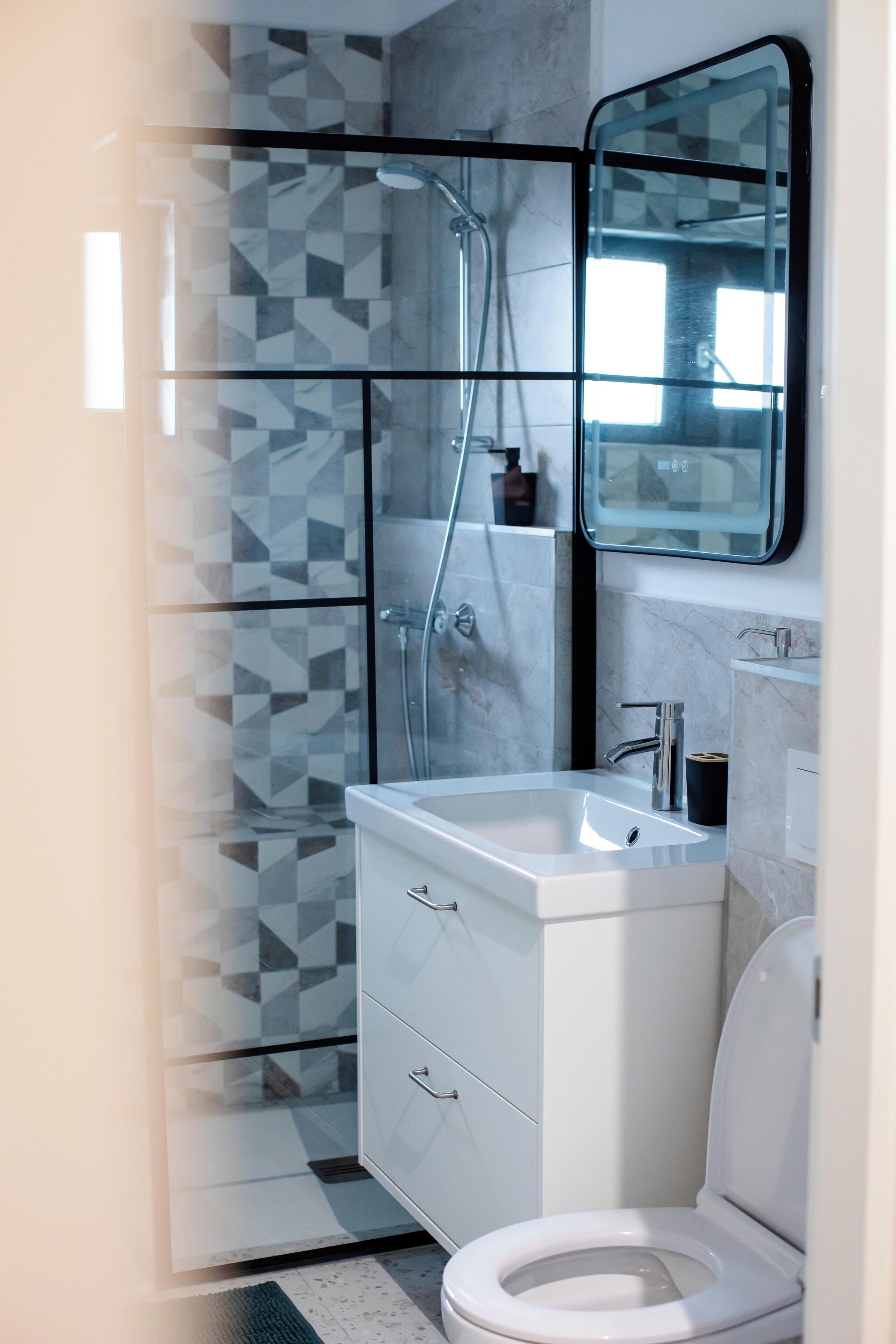 Ein modernes Badezimmer mit Duschkabine aus Glas, einem weißen Waschbecken und einer Toilette.