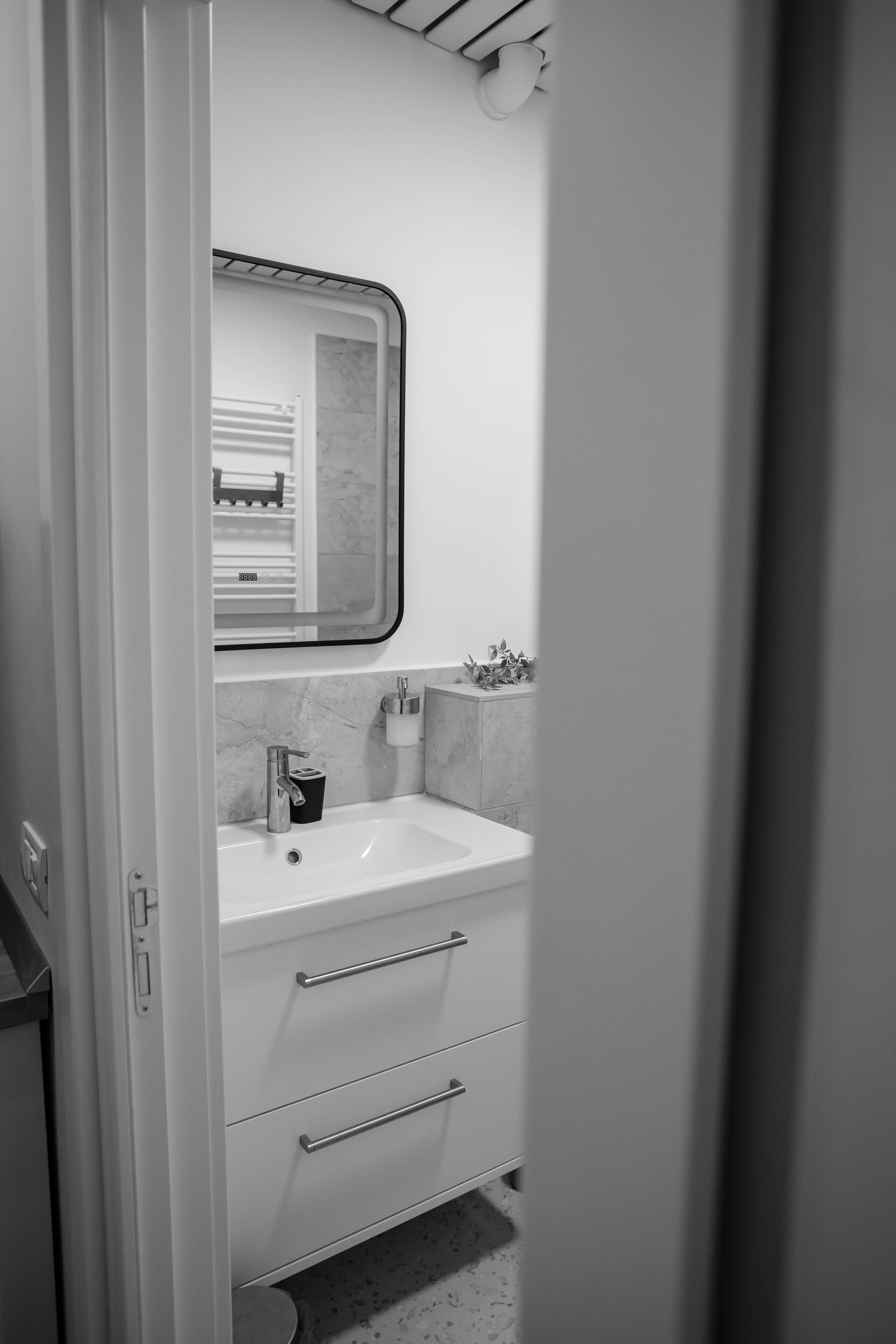 Une salle de bain avec un lavabo blanc, un miroir et un porte-serviettes.