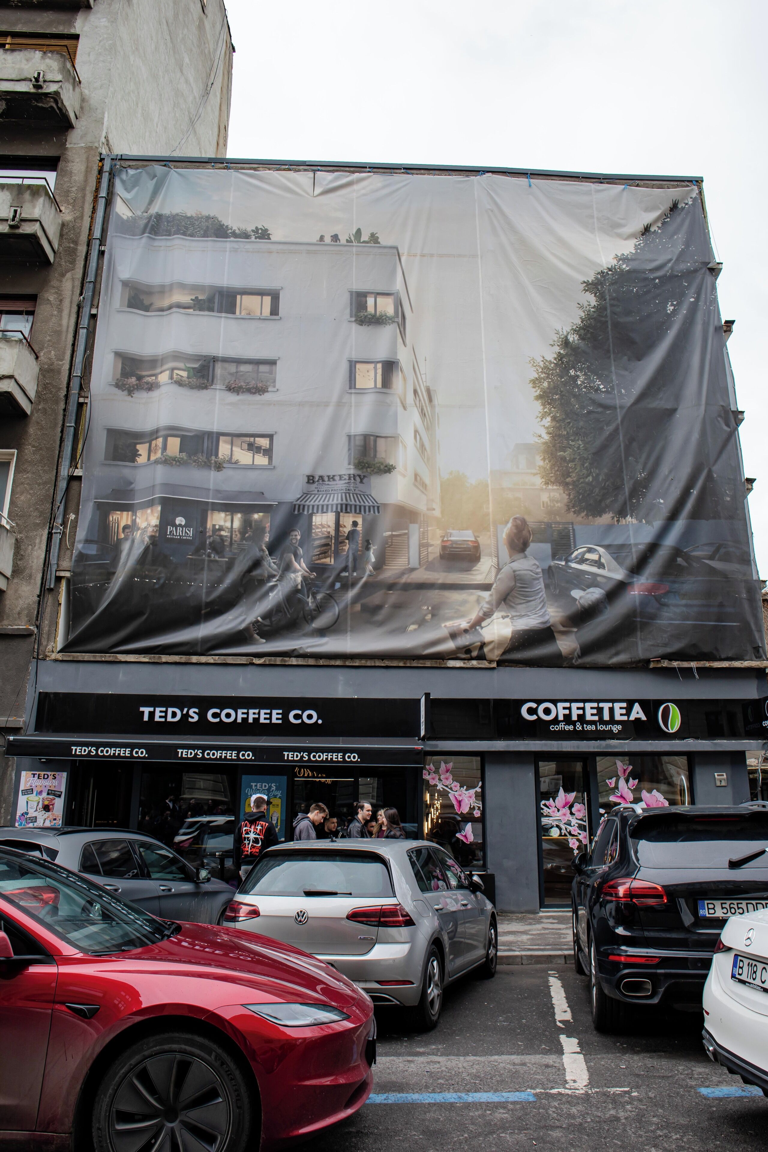 A building with a large coffee shop sign, parked cars, and a visible storefront.