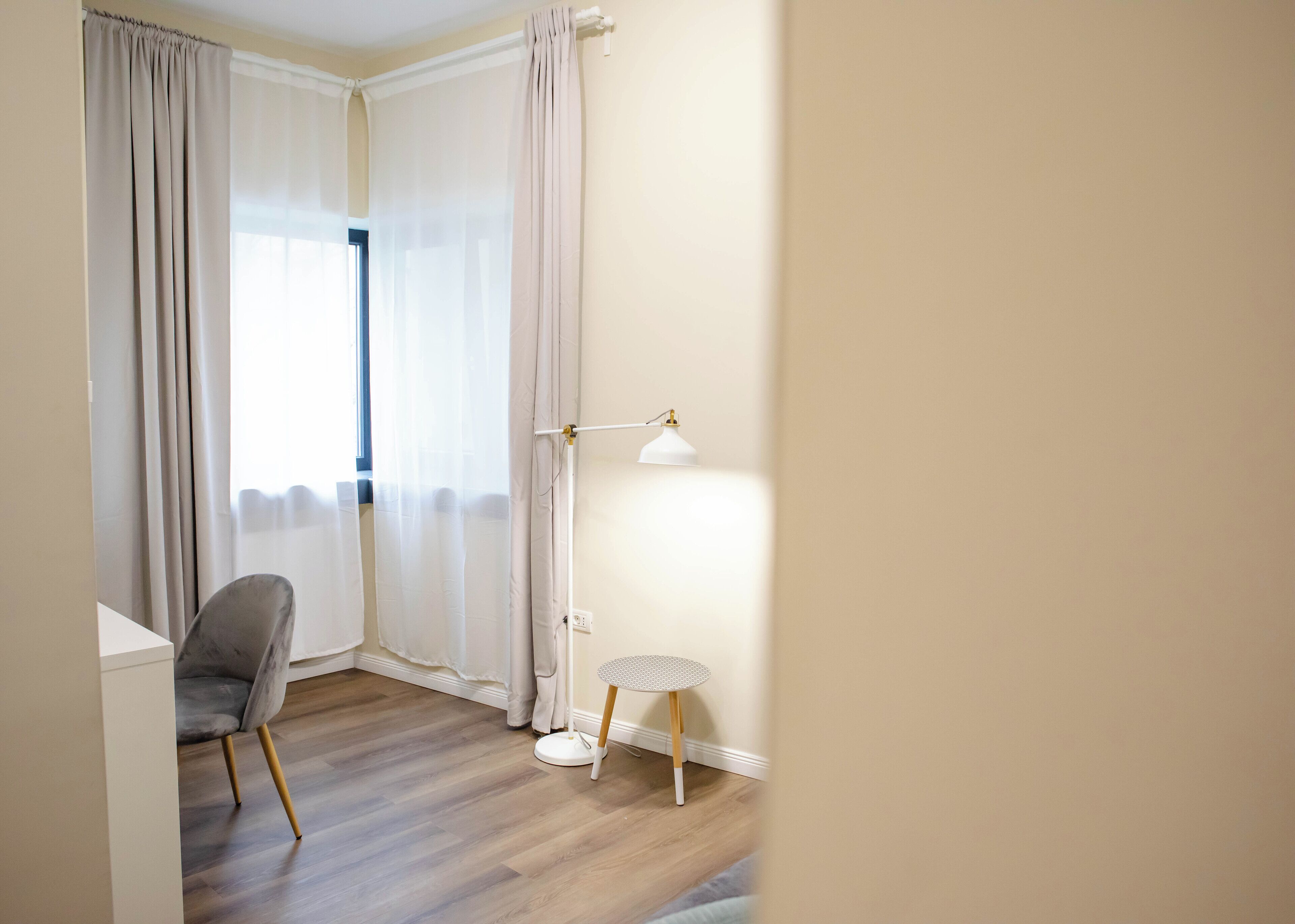 A room with a grey chair, a small round table, and a floor lamp.