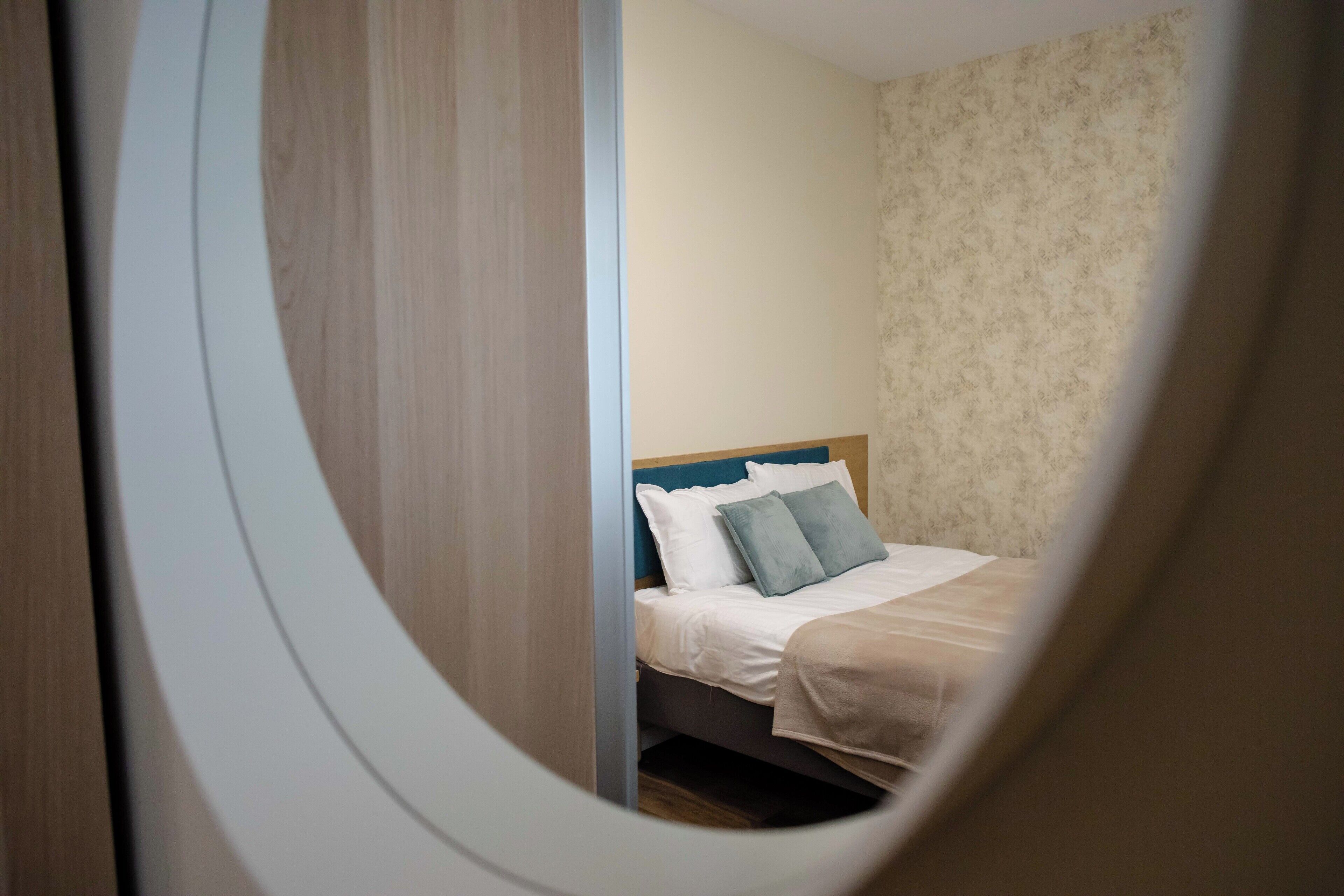 A bedroom with a bed, pillows, and a wooden headboard.
