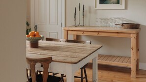 Un comedor rústico con una mesa y sillas de madera, una puerta blanca y un cuadro en la pared.