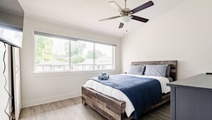 Ein Schlafzimmer mit Bett, Deckenventilator, Fenster und Schreibtisch.