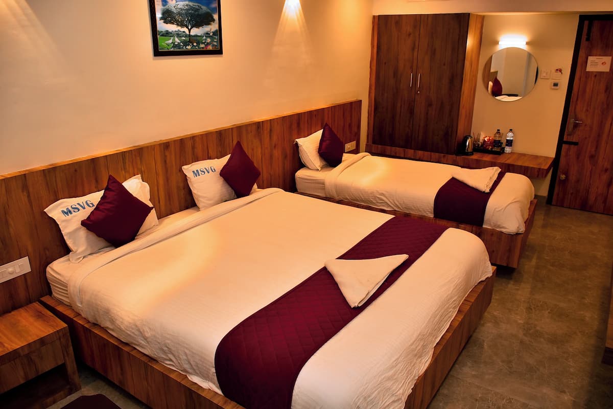 A hotel room with two beds, wooden headboards, and a wooden wardrobe.