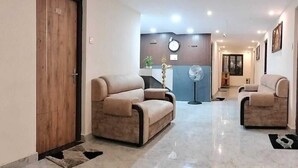 Amplia sala de estar con dos sofás color beige, una puerta de madera y suelo de mármol.