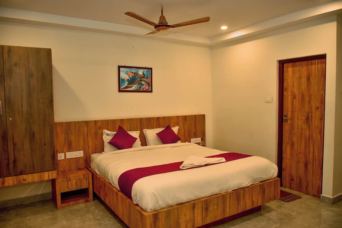 A bedroom with a wooden bed, a nightstand, a ceiling fan, and a wooden wardrobe.