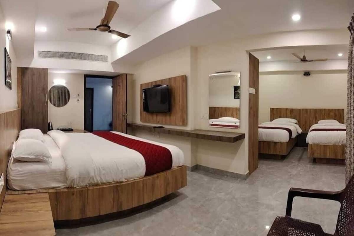 A modern hotel room with a large bed, a TV, a desk, and a seating area.