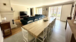 Un vaste espace de vie comprenant un grand canapé, une table à manger avec des chaises, un téléviseur à écran plat et une cheminée.