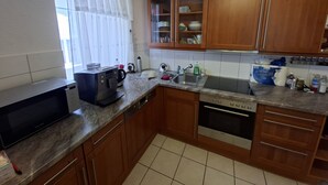 A kitchen with wooden cabinets, a microwave, a coffee maker, a sink, and a dishwasher. - Ideal for hikers, artists and nature lovers (Waldenburg)
