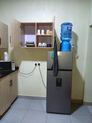 A kitchen with a refrigerator, a water dispenser, and a microwave.