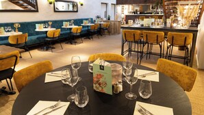 A restaurant with round tables, yellow chairs, and a bar area. - hotel restaurant LEs Boissières (Bioule)