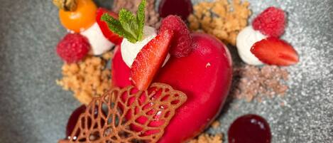 A dessert with strawberries, raspberries, and a decorative leaf on a plate.