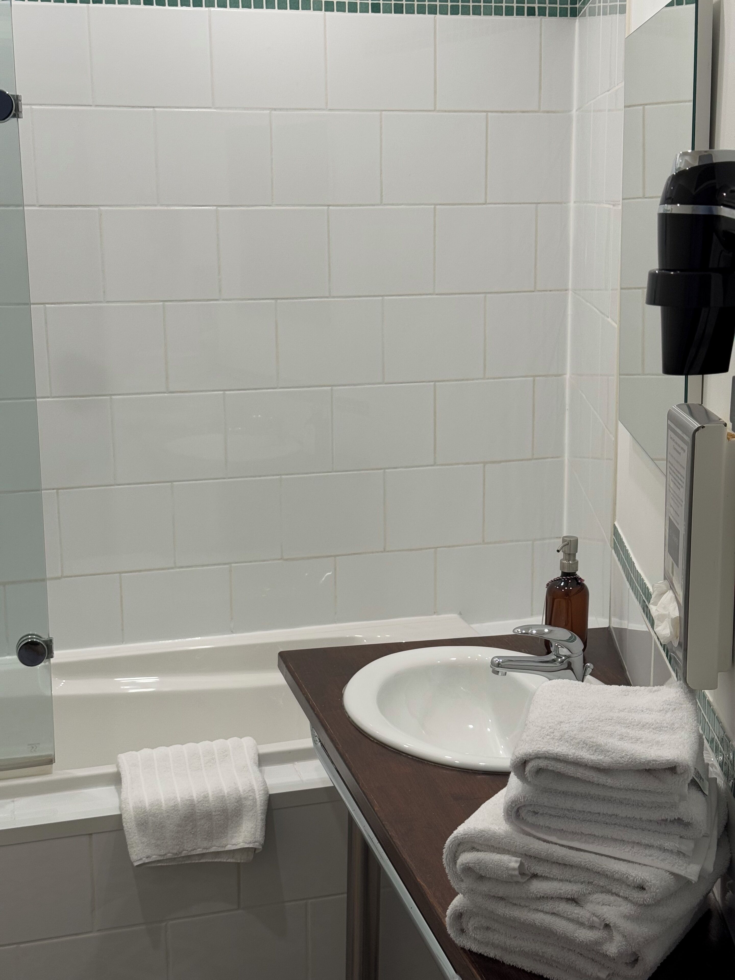 A bathroom with a white bathtub, a sink, and a towel rack with folded towels.